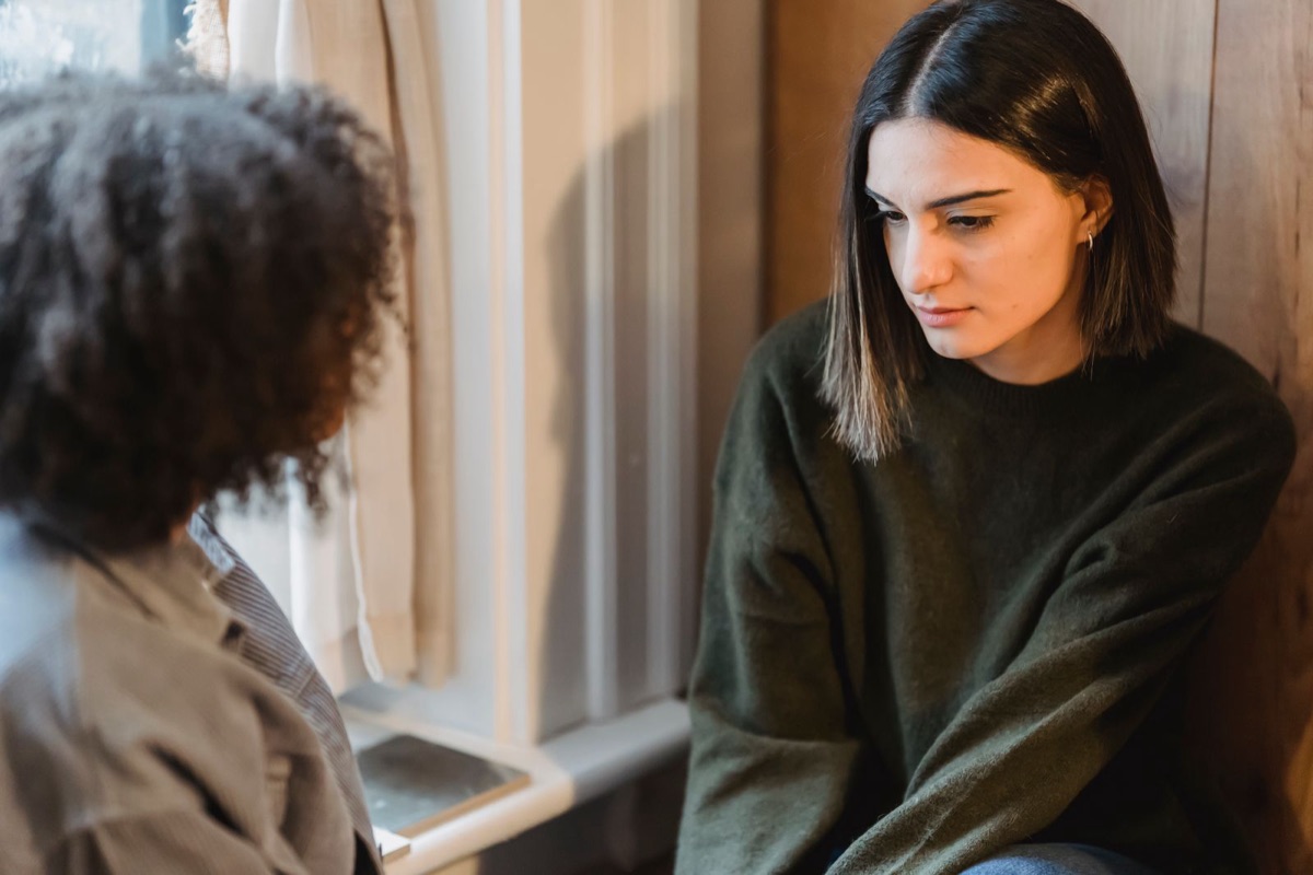 Two friends sharing a quiet conversation by a window